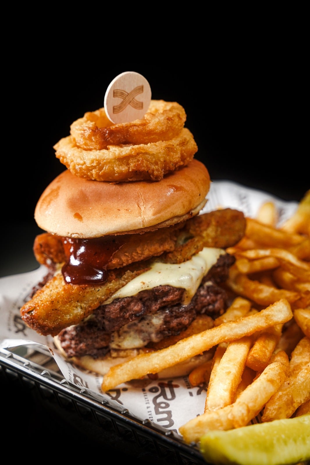 A burger with onion rings and fries at Remix